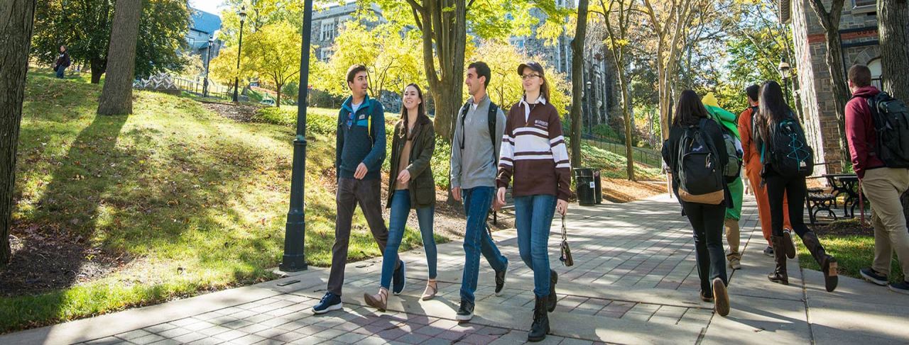 Kampüs bahçesinde yürüyen üniversite öğrencileri