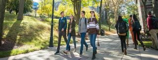 Kampüs bahçesinde yürüyen üniversite öğrencileri